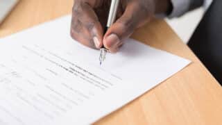 Hand with pen filling out document