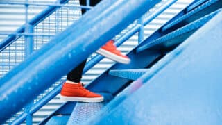 Red tennis shoes running up blue stairs