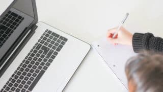 woman writing next to computer