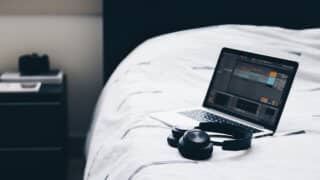 Laptop and headphones on bed