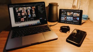 Laptop, tablet, phone, and smart watch on desk under lamp