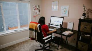 Woman in red shirt sitting at a desk in front of a computer