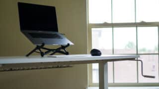 IKEA standing desk with mouse, keyboard, and MacBook on laptop stand