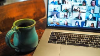 Coffee mug on table next to MacBook with Zoom call