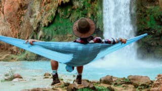Man relaxing in hammock in front of waterfall