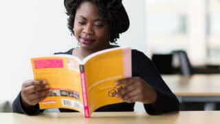 woman reading a book at a conference table