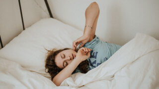 Woman waking up and stretching in bed