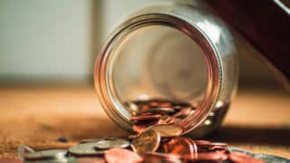 Closeup of a jar of coins spilled on the ground