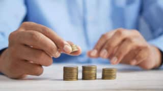 Man's hands stacking gold coins in three piles on a table