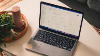 MacBook on table next to candle and plant