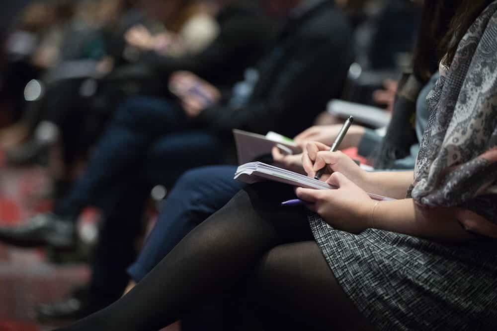 row of people taking notes