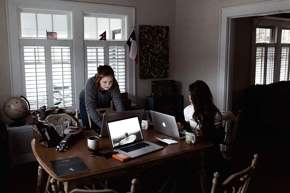 women working at laptops in dining room