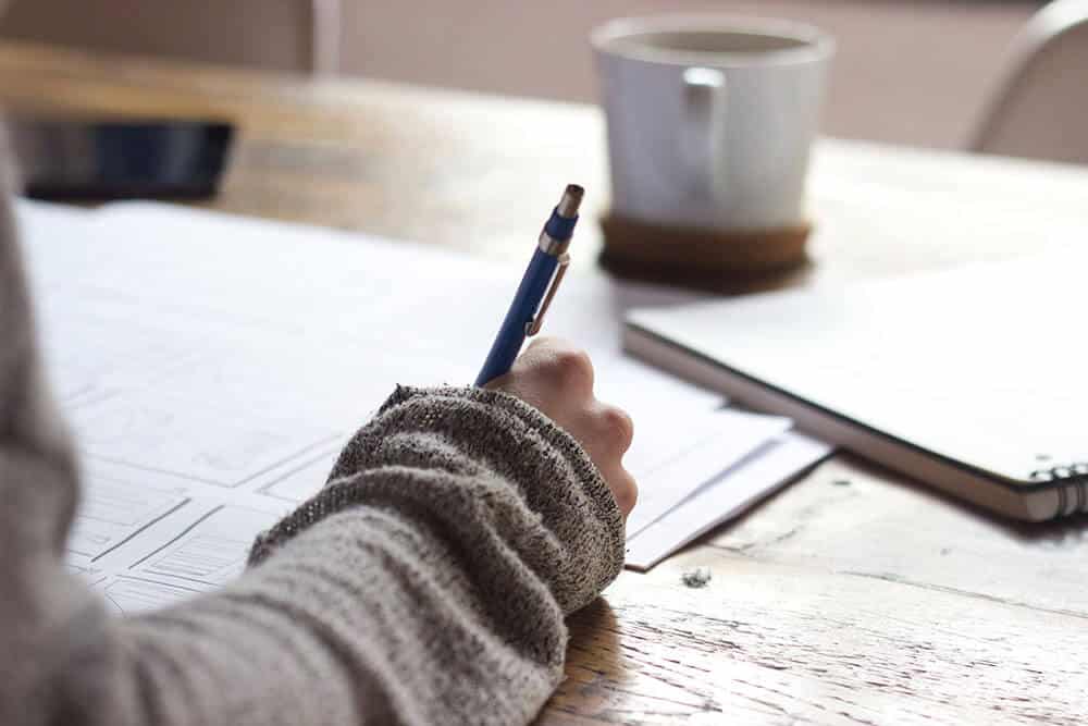 hand writing on a paper with coffee cup