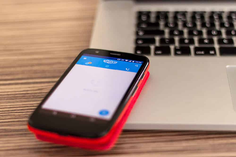 skype app open on a smartphone on top of a laptop