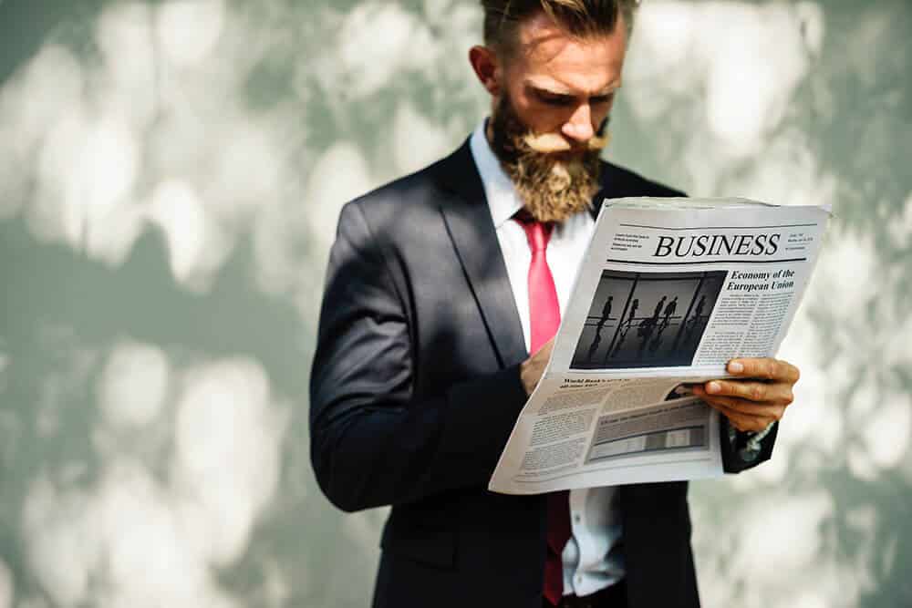 bearded man reading newspaper