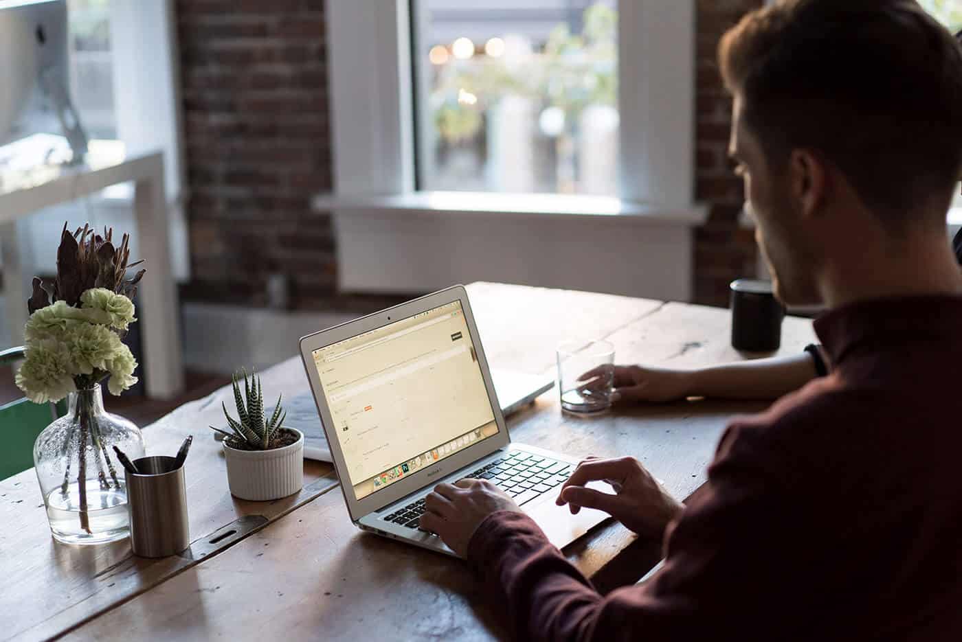 typing on a laptop at a wooden table