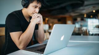 Man wearing headphones while studying in front of MacBook