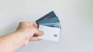 person's hand holding four credit cards