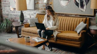 Woman working on laptop while sitting on couch