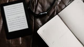 e-reader, Apple Watch, and notebook on brown leather