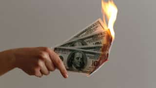 Hand holding three burning one hundred dollar bills