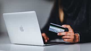 Closeup of woman's hand holding credit card in front of MacBook