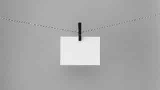 White index card hanging from black clothespin on clothesline