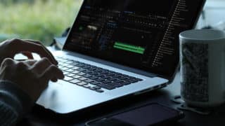 Hands typing on MacBook Pro in dim light