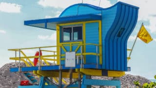 Blue and yellow lifeguard stand on beach with yellow flag