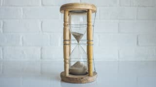 Wooden hourglass in front of white bricks